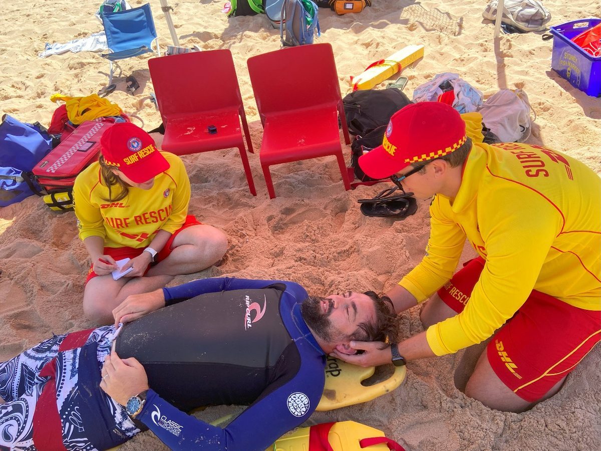 Life Saving Victoria patrol members keeping Brad still on the sand after the accident
